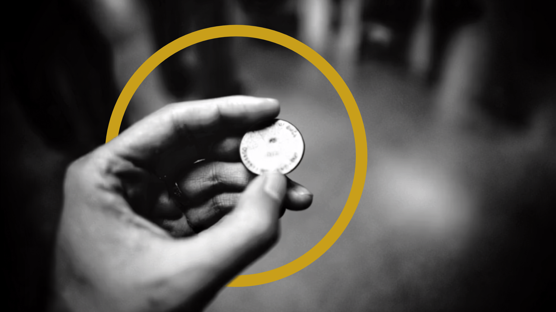 A hand holding a coin against a black and white background